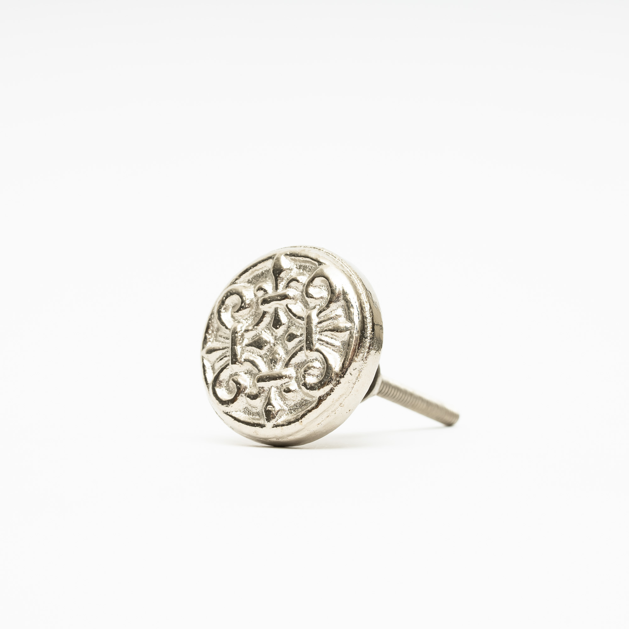 Silverfärgad knopp i metall med mönster av ornament