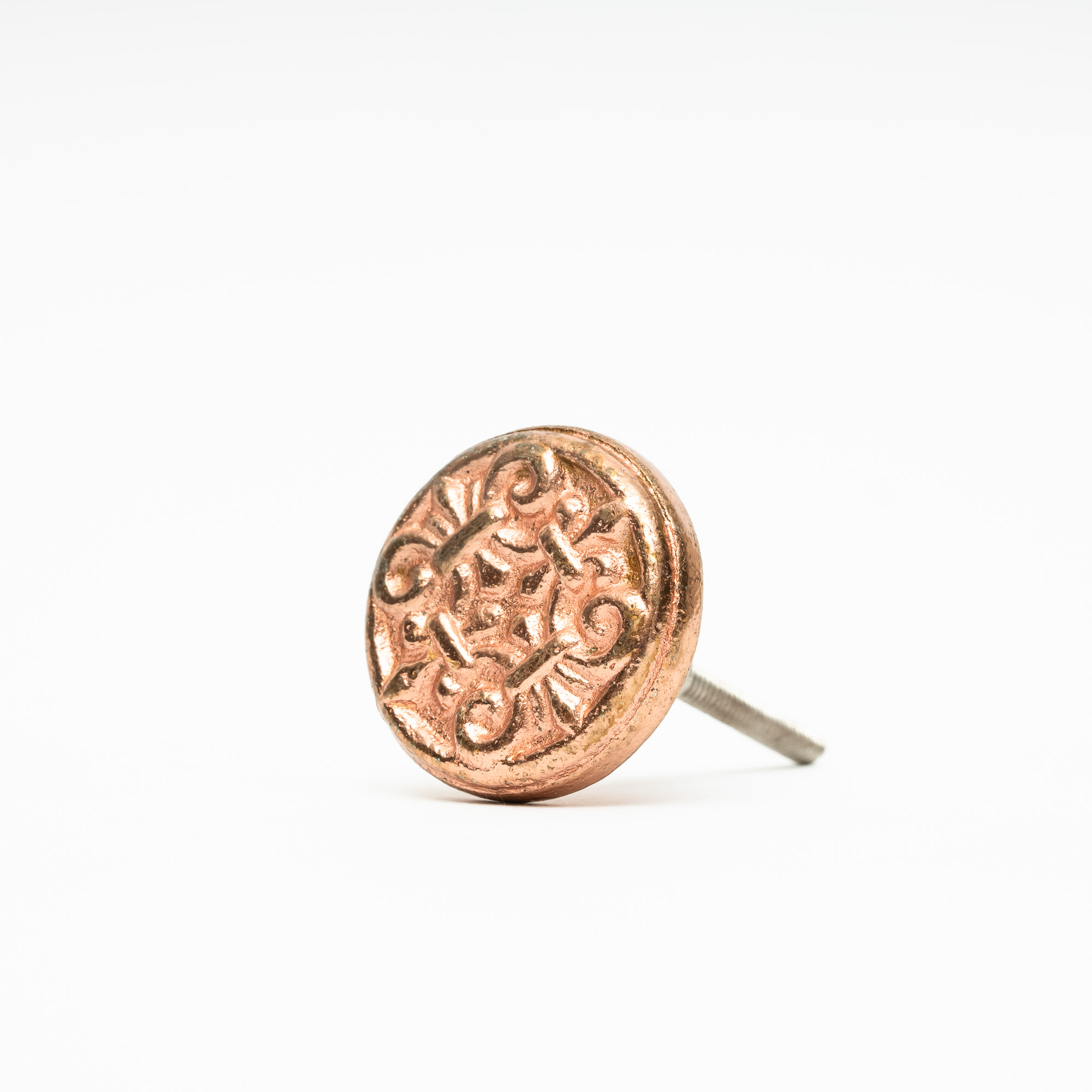 Mässingsfärgad knopp i metall med mönster av ornament