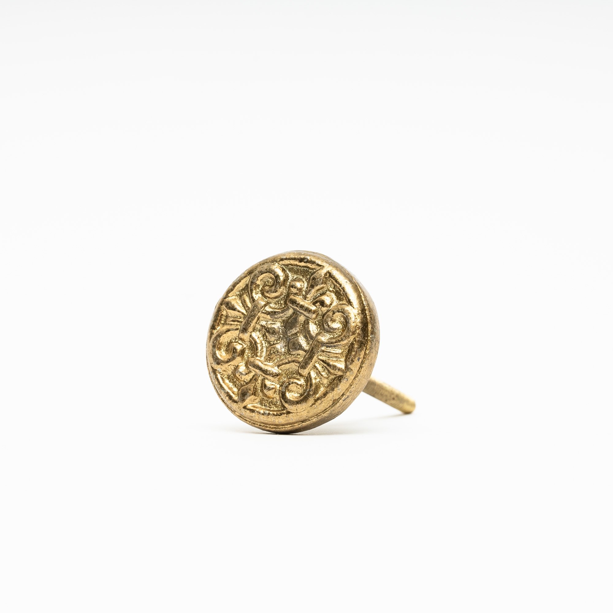 Guldfärgad knopp i metall med mönster av ornament