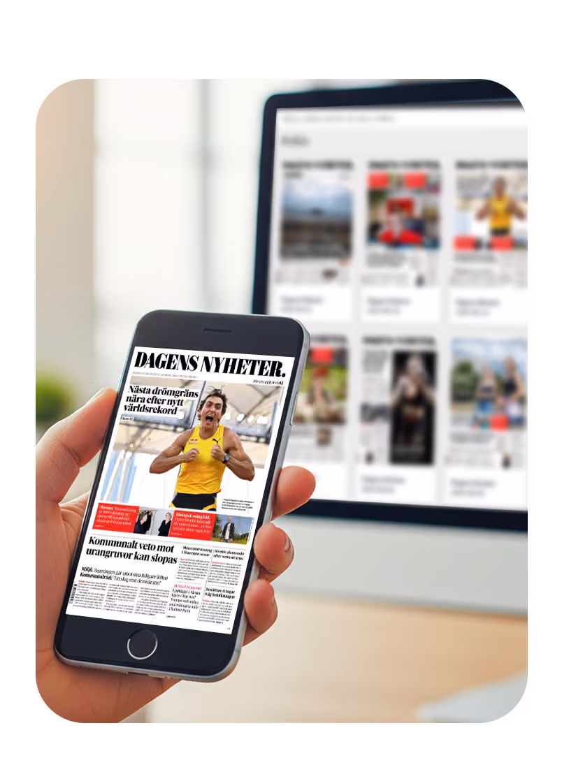 En hand håller en smartphone som visar Dagens Nyheter i Prenlys e-tidningsapp. I bakgrunden syns en datorskärm med fler digitala publikationer.