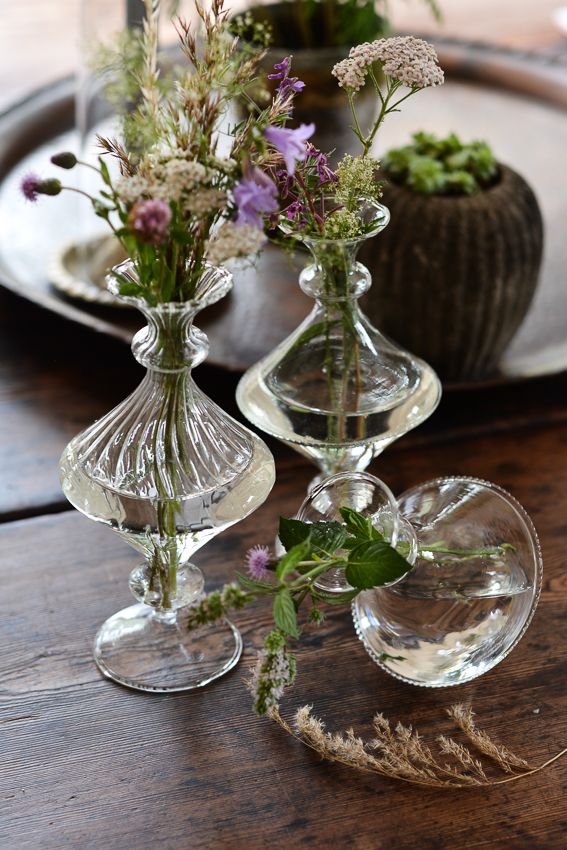 Vintage glass bud vases by Affari with wildflowers on a rustic wooden table.