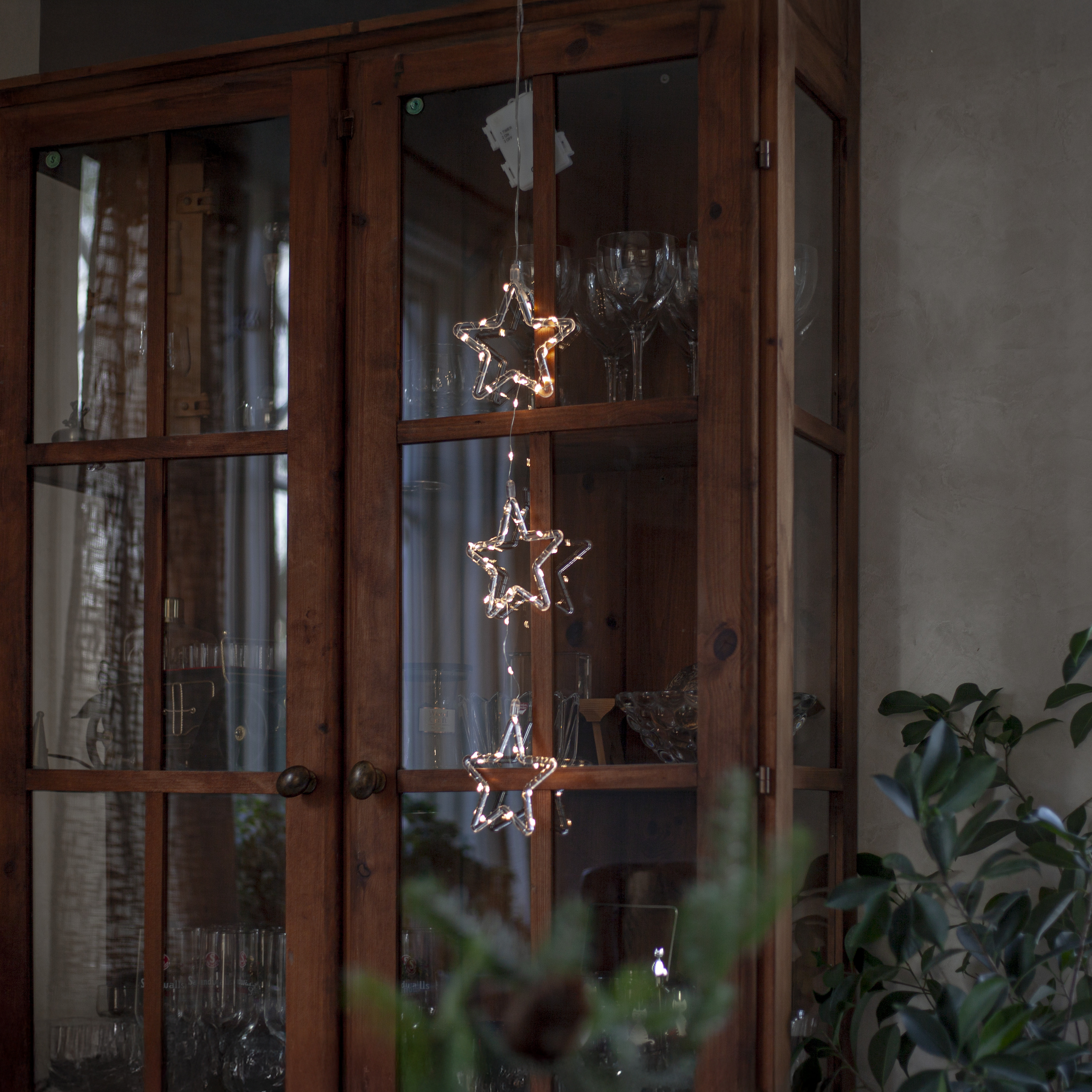 Hanging star lights Stina by Star Trading over a wooden cabinet.