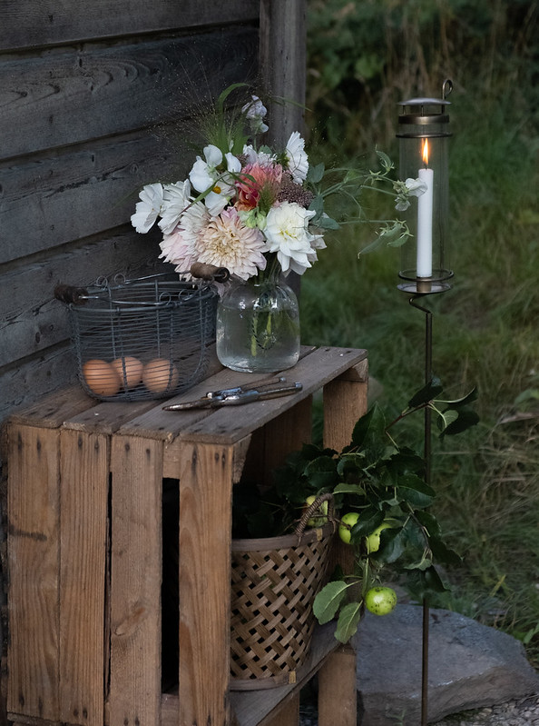 Outdoor stick candle holder by Strömshaga and a rustic wire basket in a country garden.