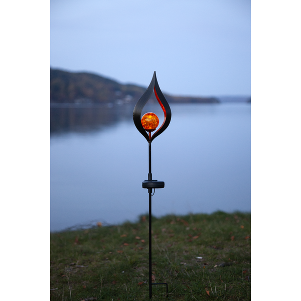 Solar lighting in a garden at dusk, lanterns along a lake.