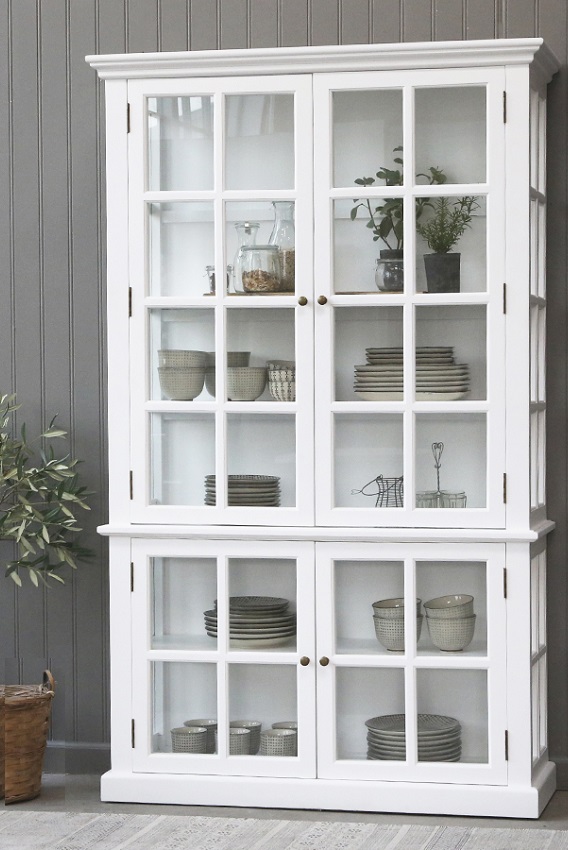 White French country glass cabinet with glazed panel doors, filled with crockery, bowls and potted herbs against a grey panelled wall