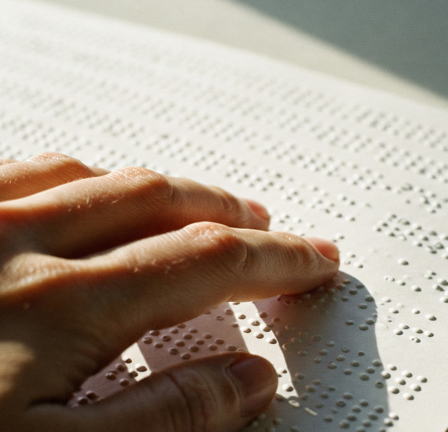 A hand moving across Braille text.
