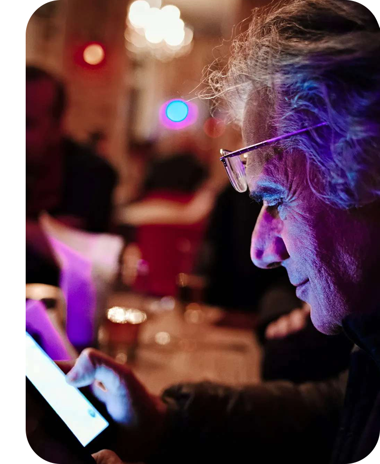 Textalk-Gründer Henryk blickt auf ein Smartphone, dessen Licht sein Gesicht in einem dunklen Raum erhellt.