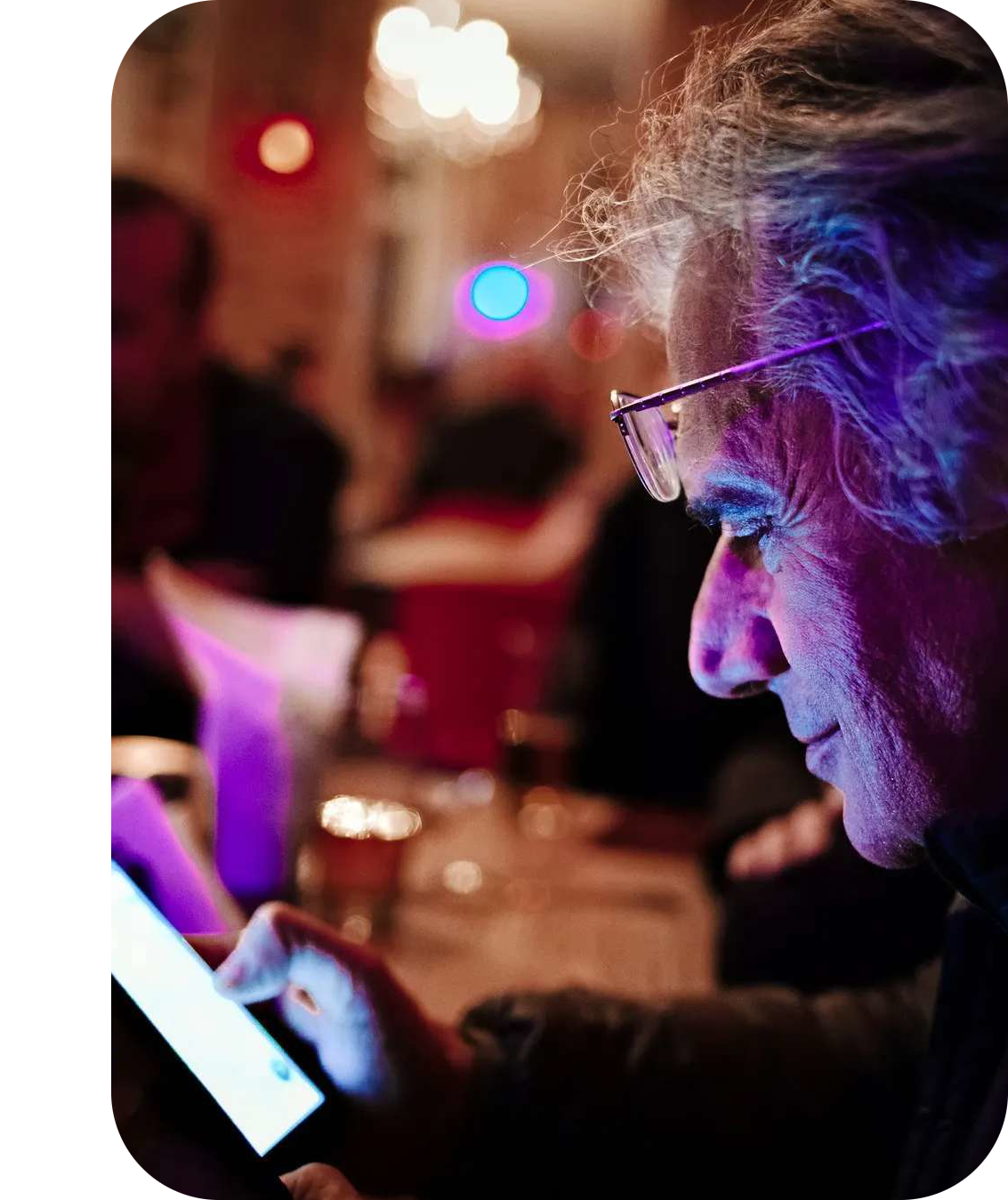 Textalk’s founder, Henryk, looking down at a phone that lights up his face with its glow in a dark room.