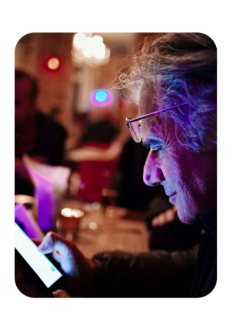 Textalk’s founder, Henryk, looking down at a phone that lights up his face with its glow in a dark room.